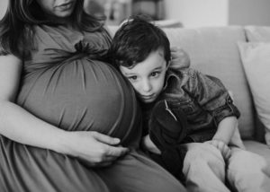 boy pressing ear against mom's baby belly